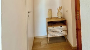 A hallway with a woven light fixture, a wooden bench with baskets, and a wooden door.