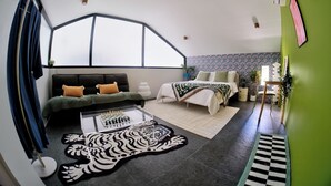 A modern bedroom with a large window, a sofa, a bed, a coffee table with chess, and a zebra-patterned rug. - Converted Chapel Villa · Private Pool + Arcade (Dumaguete City)