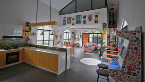 A spacious kitchen with a central island, a dining area with a pink sofa, and a children's play area with a Mario-themed wall. - Converted Chapel Villa · Private Pool + Arcade (Dumaguete City)