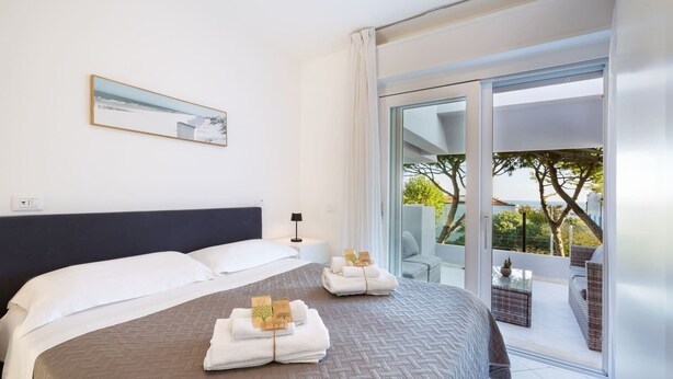 Une chambre d’hôtel avec un lit, une table de chevet, une lampe, une vue sur l’extérieur et un balcon.