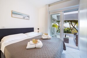 A hotel room with a bed, a bedside table, a lamp, a view of the outdoors, and a balcony. - Carinzia Luxury Top by Riviera Collection (RICCIONE)