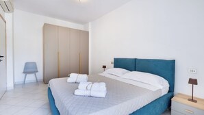 A bedroom with a bed, a chair, a wardrobe, and a nightstand. - Carinzia Comfort Plus 8 - Riviera Collection (RICCIONE)