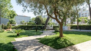A paved pathway, green grass, and trees in a courtyard. - Carinzia Comfort Plus 8 - Riviera Collection (RICCIONE)