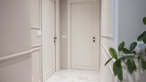 Ein Flur mit zwei weißen Türen, einer weißen Wand und einem Blumentopf.