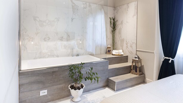 Ein modernes Badezimmer mit großem Spiegel, einer Badewanne und einer Topfpflanze.