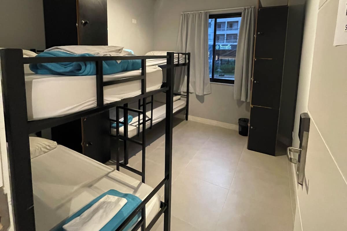 A compact room with bunk beds, a wardrobe, a window with curtains, and a door.