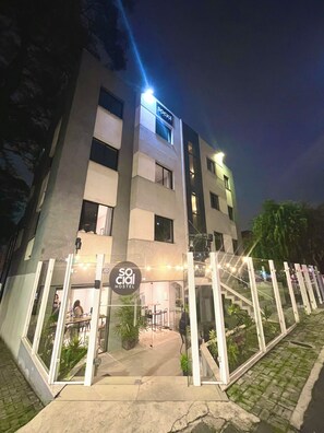 A modern hostel with a glass entrance, outdoor seating, and a staircase leading to the entrance. - Social Hostel (Curitiba)