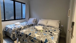 Ein Hotelzimmer mit zwei Betten, einem großen Fenster und einer Tür.