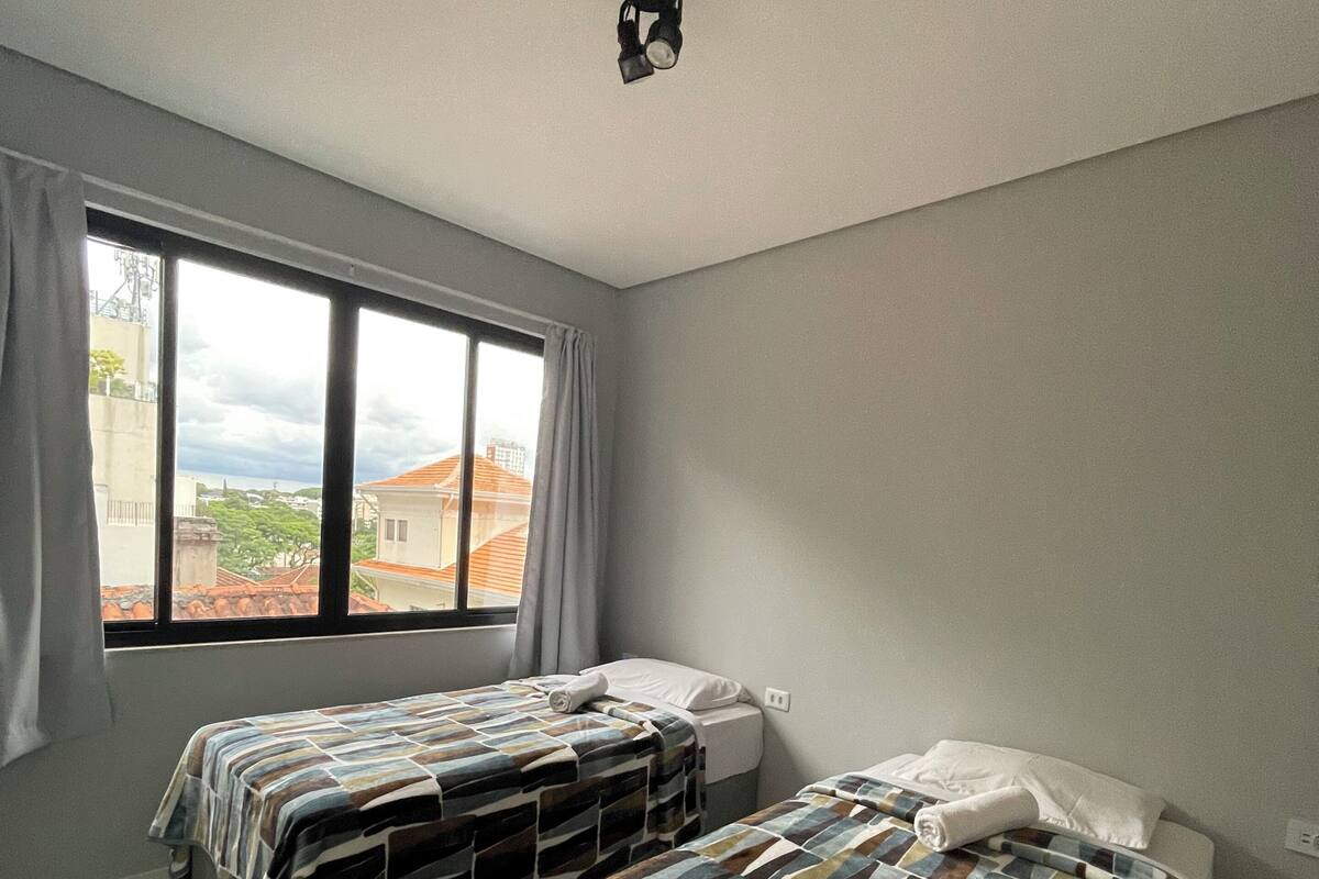 A room with two beds, a window, and a ceiling light.