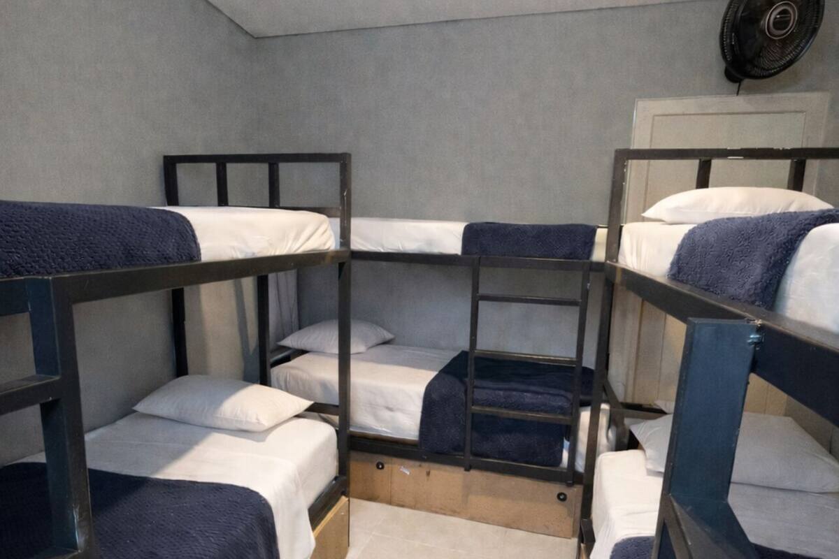 A room with bunk beds, a ceiling fan, and a tiled floor.