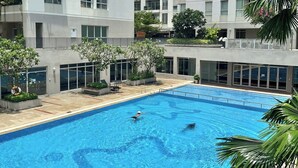 A swimming pool surrounded by modern buildings with balconies, large windows, and some greenery. - Apartment in District 7 Near SECC (Thành phố Hồ Chí Minh)