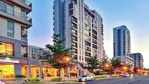 A modern high-rise building with multiple balconies and a ground-level cafe. - Apartment in District 7 Near SECC (Thành phố Hồ Chí Minh)