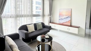 A modern living room with a sofa, a coffee table, and a painting on the wall. - Apartment in District 7 Near SECC (Thành phố Hồ Chí Minh)