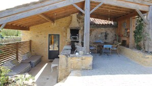 Eine rustikale Außenpatio mit Steinsitzen, einem Tisch und einem Grillbereich.