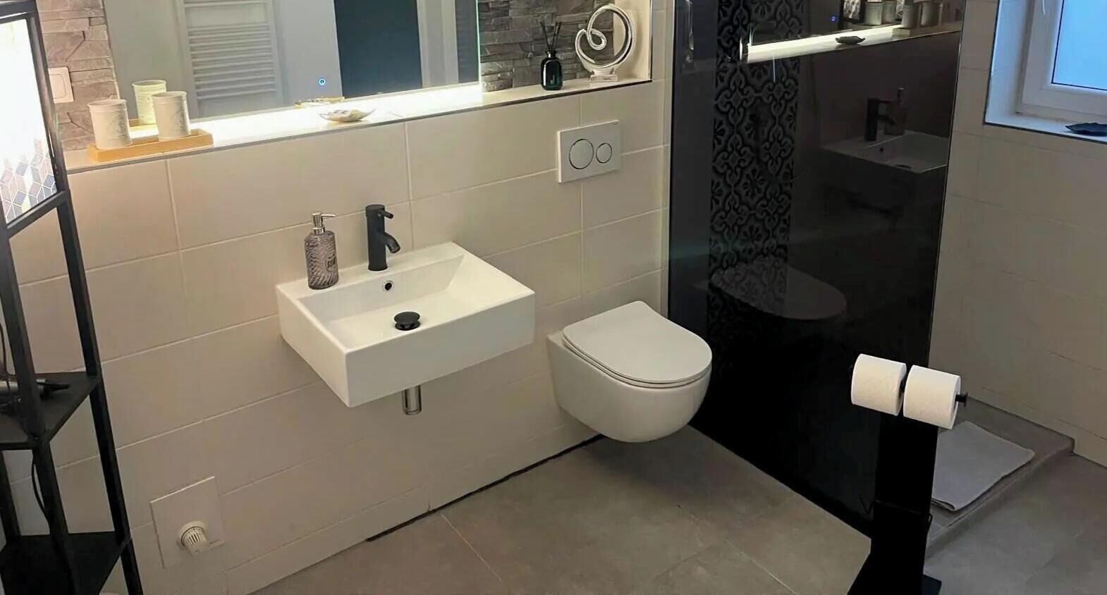 Un baño moderno con lavamanos, inodoro y cabina de ducha de vidrio.
