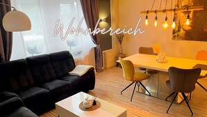 Ein modernes Wohnzimmer mit einem schwarzen Sofa, einem weißen Couchtisch und einem Essbereich mit gelben Stühlen.