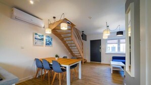 Una cocina moderna con una mesa y sillas de madera, una escalera e iluminación colgante.