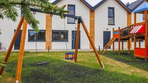Un edificio residencial de diseño moderno, con un columpio y una pequeña zona de juegos en el patio.