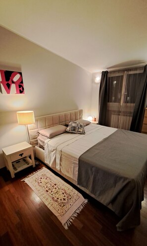 Ein Schlafzimmer mit Bett, Nachttischen, einer Lampe, einem Teppich und einer Wanddekoration.