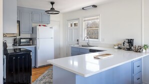A modern kitchen with a central island, built-in appliances, and a window providing natural light. - Treetop Tides, Sound View and Canal Front 4BR 3BA Emerald Isle! (Emerald Isle)