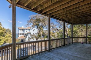 A covered wooden deck with a view of a house and trees. - Treetop Tides, Sound View and Canal Front 4BR 3BA Emerald Isle! (Emerald Isle)