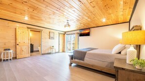Een kamer met houten lambrisering, een bed, een kleine tafel en een lamp.
