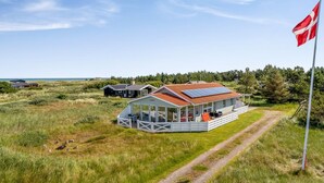 Et kysthus med et glaskonservatorium, rødt tag og flagstang.