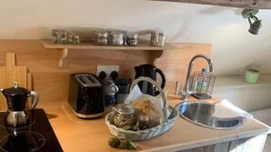 A kitchen with a coffee maker, toaster, kettle, and a sink. There are jars on a shelf above the counter. - Little Rissington, Pets, Parking, Sleeps 2 (Cheltenham)