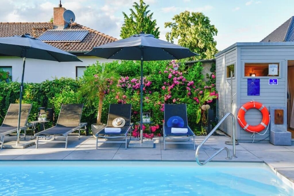 A swimming pool area with lounge chairs, umbrellas, and a lifebuoy.
