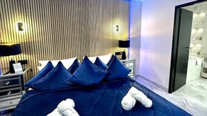 Ein Hotelzimmer mit Bett, Kissen, Nachttisch, Lampe und Spiegel.