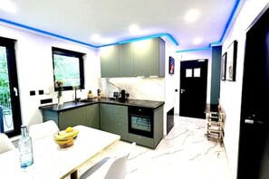 A modern kitchen with dark cabinets, a marble countertop, and a dining area with a table and chairs. - Adina vacation apartment (Teltow)
