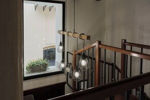 A staircase with a wooden handrail and a window with a view of a building and plants outside. - Nina's Cattedrale House—The Heart of Palermo, Where History Meets Comfort (Palermo)