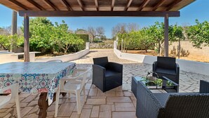 An outdoor patio with wicker furniture, a tiled table, and a view of a vineyard. - Villetta Murena - Con Piscina Privata E Vista Mare (Corsano)