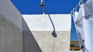 A small, tiled shower area with a showerhead and faucet, a curtain, and a view of a green lawn. - Villetta Murena - Con Piscina Privata E Vista Mare (Corsano)