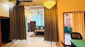 A room with a dining table and chairs, a chandelier, and curtains. - Brightness in the Sky – A Cozy, Peaceful Stay with Modern Comforts (Jaipur)
