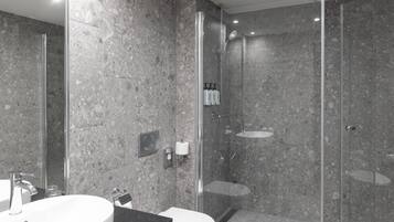 Een moderne badkamer met een douchecabine van glas, een wastafel en een toilet.