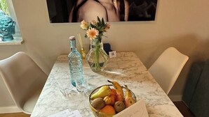 Een marmeren tafel met een fruitmand, een waterfles en een bloevas.