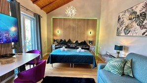 A modern bedroom with a bed, a TV, a desk, and a sofa. - Vacation apartment Luna (Teltow)