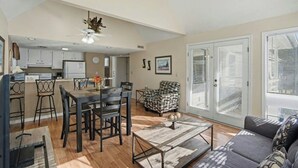 A spacious living room with a dining area, a patterned armchair, and a sofa. - Arcadian Dunes 11 #343- 2BR- Pool, Hot Tub (Myrtle Beach)