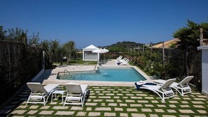Ett poolområde med solstolar och en pergola.