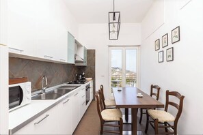 Eine moderne Küche mit weißen Schränken, einer eingebauten Mikrowelle und einem Essbereich mit Holztisch und Stühlen.