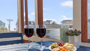 A table with two glasses of red wine, a plate of cheese, crackers, and grapes, and a succulent plant. - Ocean Edge 204- Cherry Grove 2BR- Pool (North Myrtle Beach)