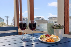 Ein Tisch mit zwei Gläsern Rotwein, einem Käseplatte, Crackern und Trauben, sowie einer saftigen Pflanze.