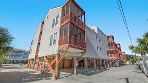 A modern multi-story building with balconies, a flat roof, and a concrete ground floor. - Ocean Edge 204- Cherry Grove 2BR- Pool (North Myrtle Beach)