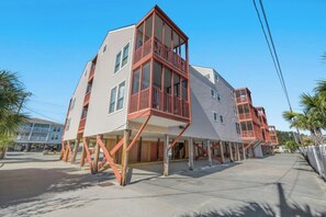 Ein modernes Mehrgeschosshaus mit Balkonen, einer flachen Dachterrasse und einem Beton-Erdgeschoss.