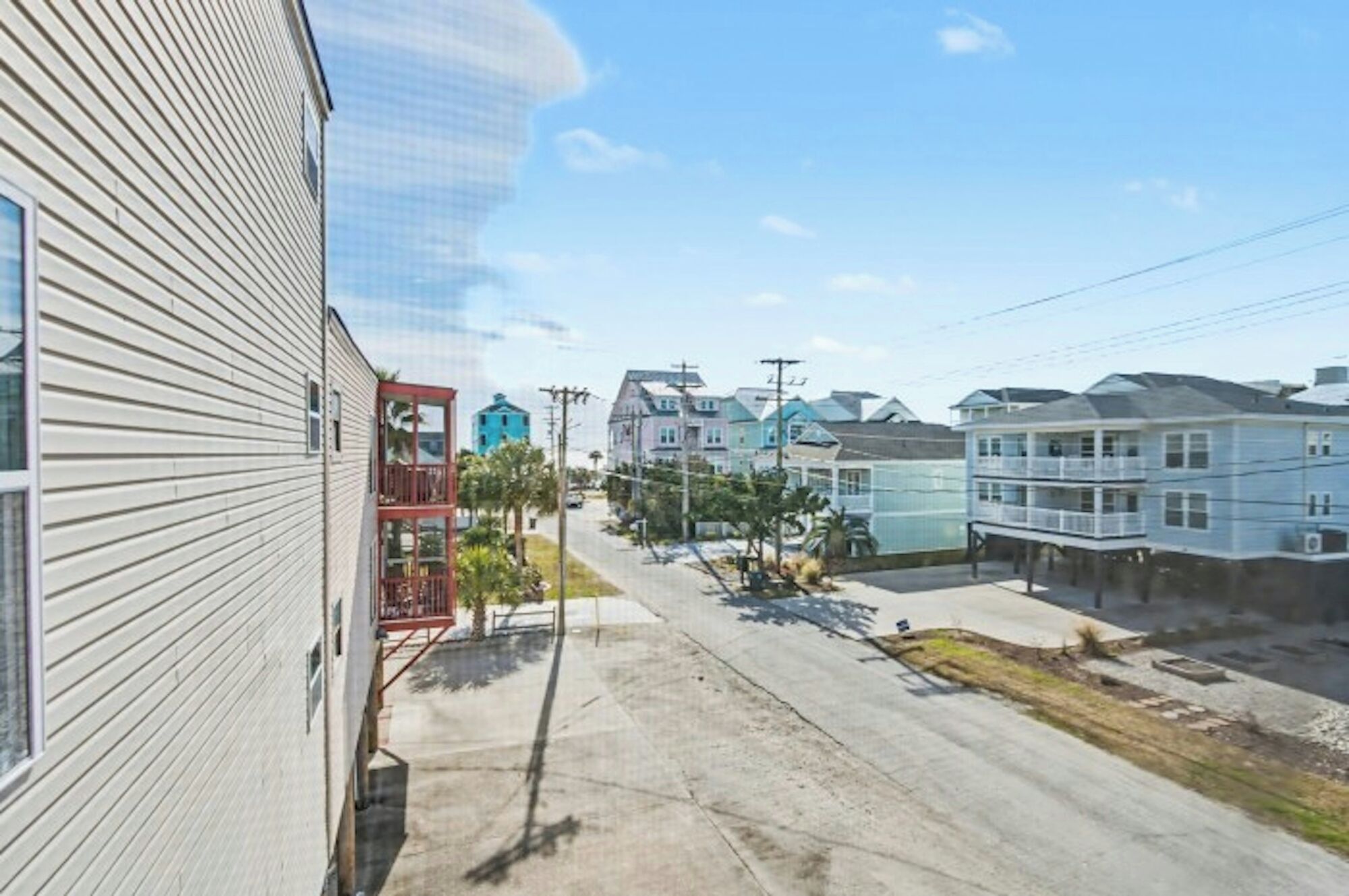 Une rue résidentielle bordée de maisons, un ciel dégagé et un château d’eau visible à l’arrière-plan.