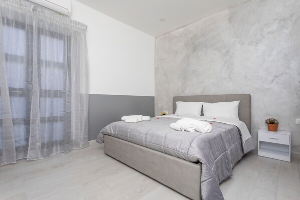 A modern bedroom with a bed, a nightstand, a potted plant, and a sheer curtain. - Pm House – Double Room (Misterbianco)