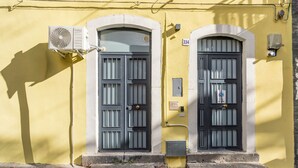 A building with two arched doors, a small step leading to the entrance, and an air conditioning unit mounted on the wall. - Pm House - Suite with Jacuzzi (Misterbianco)