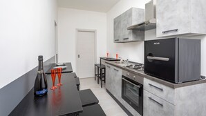 A modern kitchen with a built-in stove, oven, and a refrigerator. - Pm House - Suite with Jacuzzi (Misterbianco)