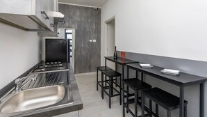 A modern kitchen with a stainless steel sink, black bar stools, and a black countertop. - Pm House - Suite with Jacuzzi (Misterbianco)